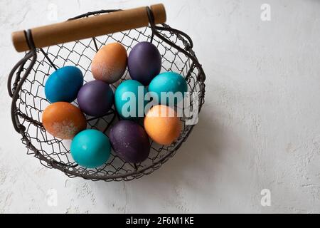 Easter eggs in a bowl in blue, turquoise, purple, and orange, and brioche shaped like an easter bunny. Stock Photo