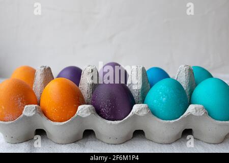 10 colorful Easter Eggs in blue, turquoise, purple, and orange in an egg carton. Stock Photo