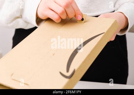 Close up woman hands opening a parcel from Amazon, March 2021, Prague, Czech Republic Stock Photo