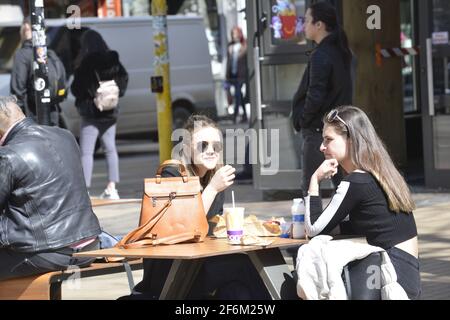 Sofia, Bulgaria - Apr 1 2021: Two girls eating outside enjoying the ease of the restrictions Stock Photo