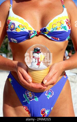 Antigua, young woman in bikini bathing suit holding a snow globe, winter get away concept image. Stock Photo