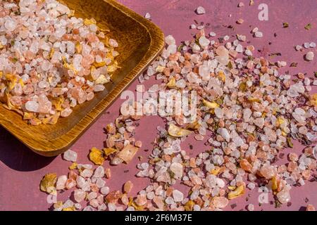 Macro photo. Pink Himalayan crystal salt spice on a wooden spoon, close-up. Rose stone background. High quality photo Stock Photo