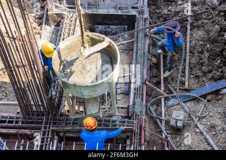 Worker pouring cement pouring into foundations formwork at the building area in a construction site. Stock Photo