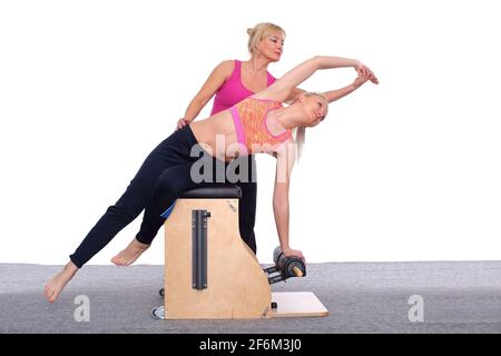 A 50-year-old trainer teaches a young girl to practice Pilates on