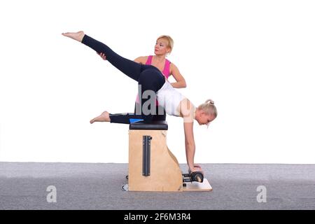 A 50-year-old trainer teaches a young girl to practice Pilates on an