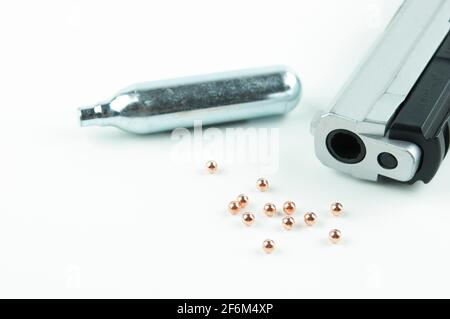 Air Gun, Co2 Cartridges and Pellets Isolated on White Background. Focus on a gun barrel. Stock Photo