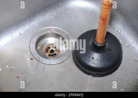 Plunger and clogged kitchen sink. Pipe cleaning concept. Sanitary engineering work. Stock Photo