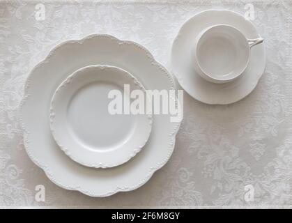 White Porcelain Place Setting on White Tablecloth Stock Photo