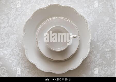 White Porcelain Place Setting Stacked on White Tablecloth Stock Photo
