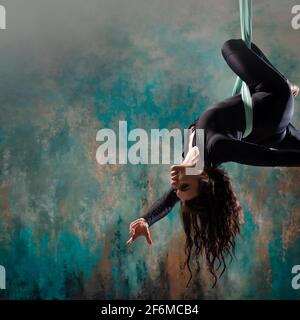 Young brunette sportswoman hanging on still rings and doing L sits