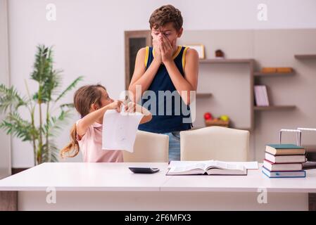 Teenager and his small sister staying at home during pandemic Stock Photo