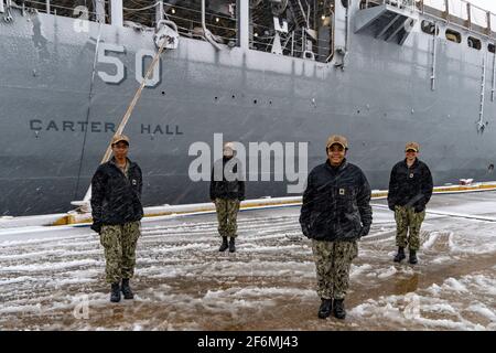 U.S. Navy commanding officers from left to right: Cmdr. Kimberly Jones, Cmdr. LaDonna M. Simpson, Cmdr. Kathryn Wijnaldum, and Cmdr. Kristel O'Canas, pose in front of the Harpers Ferry-class amphibious dock landing ship USS Carter Hall January 28, 2021 in Virginia Beach, Virginia. The group are the first four women of color to command warships in the U.S. Navy. Stock Photo