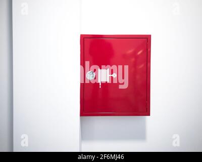Red fire hose reel cabinet on wall Stock Photo