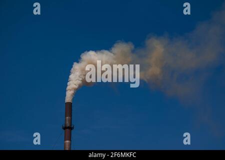 Smoke from chemical factory chimney on cloudy sky background. Ecology theme. Stock Photo