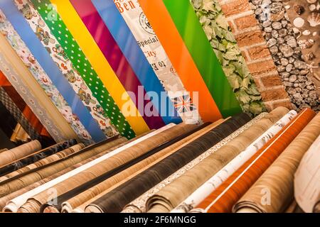 Belarus, Minsk - December 19, 2019: Different samples of color wallpaper material in rolls for interior design in the store. Stock Photo