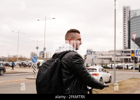Young man with backpack on his back riding on scooter Stock Photo