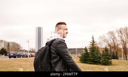 Young man with backpack on his back riding on scooter Stock Photo