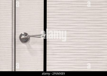 Modern white wooden door with abstract light patterns close-up, metal door handle. Stock Photo