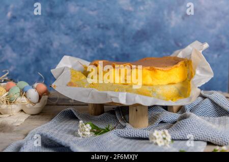 Portuguese sponge cake wrapped in the typical paper used on the baking, on wooden background with painted easter eggs decoration. Stock Photo