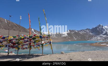 Panoramic view of Gurudongmar Lake with mountains in background and Tibetan prayer flags in the foreground in North Sikkim India on 22 November 2016 Stock Photo