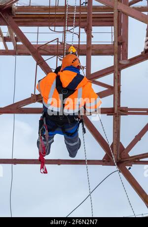 man working on high telecommunication tower. personal protection equipment, signal suit. Stock Photo