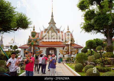 Tourists taking selfies in front of the entrance to Wat Arun, Temple of Dawn, guarded by two Giant Yaksha Statues, or Demon Guardian statue. Stock Photo