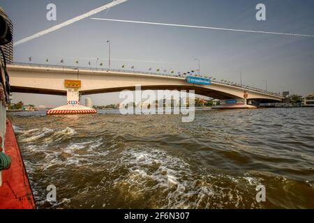 passing under the Phra Pin Klao Bridge on a long boat water taxi, while cruising along the Chao Phraya River in Bangkok, Thailand Stock Photo