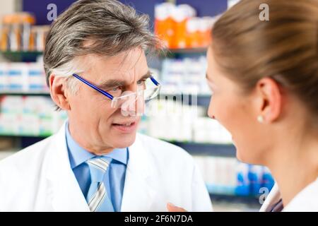 Two pharmacists with prescription in hand consulting each other in a pharmacy Stock Photo