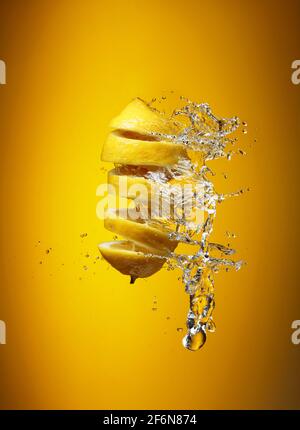 Fresh lemon and splashes on a yellow background. Stock Photo