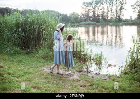 A girl stands on the shore of the lake and looks at nutria in the water Stock Photo