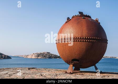 Old rusty sea mine standing on cliff Stock Photo