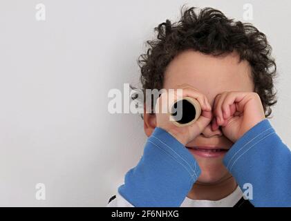 boy looking through  binoculars paper roll  on white background stock photo Stock Photo