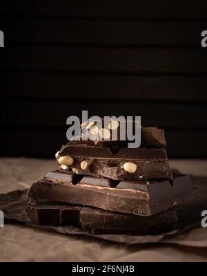 Dark chocolate with almonds and hazelnuts in a stack on brown background Stock Photo