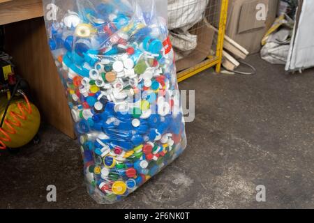 Many multicolored plastic caps from water pet bottles collected in bag for recyclyng and reuse. Environmental protection from pollution Stock Photo