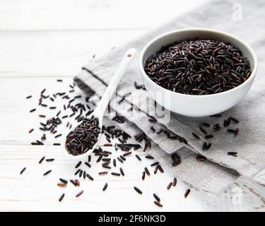 A bowl of uncooked wild rice on a  white wooden background Stock Photo