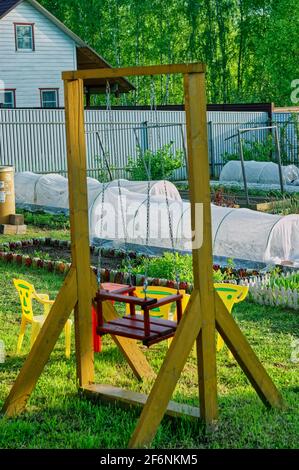 children's wooden swings in the village, spring Stock Photo