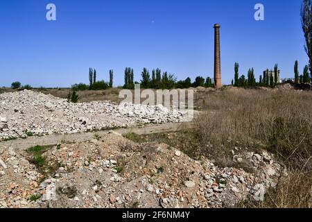 Ruins of an abandoned demolished old plant with high rise chimney. Ruined factory in  Ukraine Stock Photo