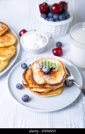 Cottage cheese pancakes (syrniki). Homemade cheesecakes from cottage cheese with sour cream, berries and milk. Traditional Russian dish. Close-up. Stock Photo