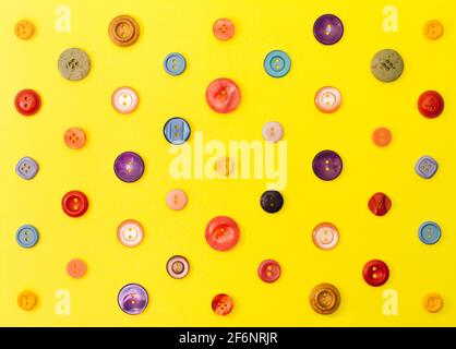 Old buttons layed out in a colorful pattern on a yellow background. Creative flat lay retro look. Stock Photo