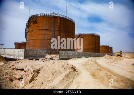 Rusted oil storage tanks on sand and blue sky background. Asphaltic bitumen plant. Stock Photo