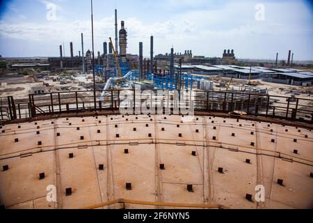 Rusted oil storage tanks on blue sky background. View from tank's roof. Asphaltic bitumen plant. Stock Photo