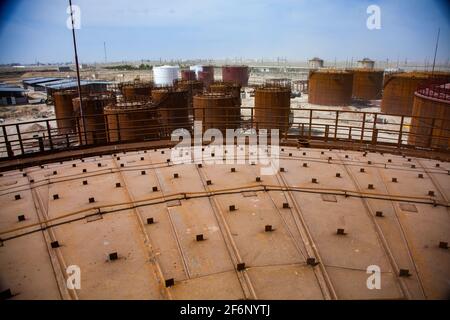 Rusted oil storage tanks on blue sky background. View from tank's roof. Asphaltic bitumen plant. Stock Photo