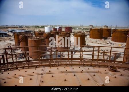 Rusted oil storage tanks on blue sky background. View from tank's roof. Asphaltic bitumen plant. Stock Photo