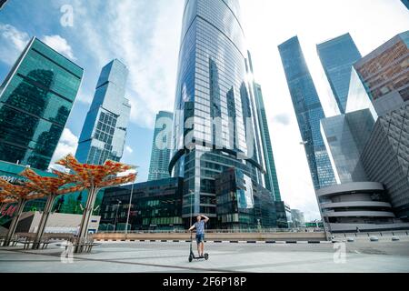 Moscow, Russia - July 12, 2020: A man rides an electric scooter around Moscow City. Vacation concept.