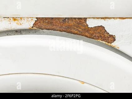 Element of an old white washing machine with a trace of rust close-up. Stock Photo
