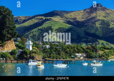 French Bay in Akaroa Harbour, New Zealand. On the left is a historic lighthouse dating back to 1880 Stock Photo