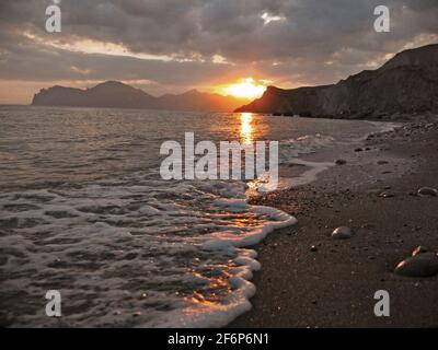 An epic sunset on the sea - the sun sets behind the mountain and ...