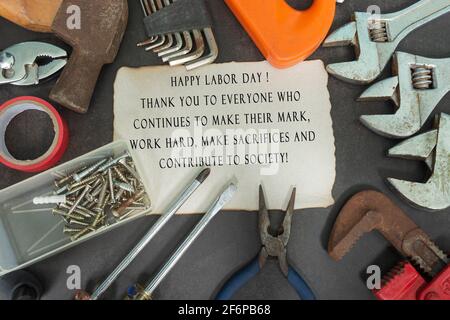 Text on burned edge paper with repair equipment and many handy tools on a dark background. Labor day concept Stock Photo