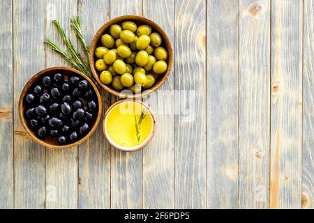 Olives in wooden bowl with oil and rosemary leaves, top view Stock Photo