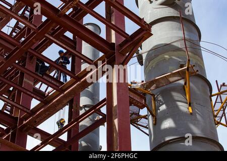 Aktau, Kazakhstan - May 19, 2012 Construction of modern asphaltic bitumen plant. Close-up of industrial building structure. Workers and grey refinery Stock Photo
